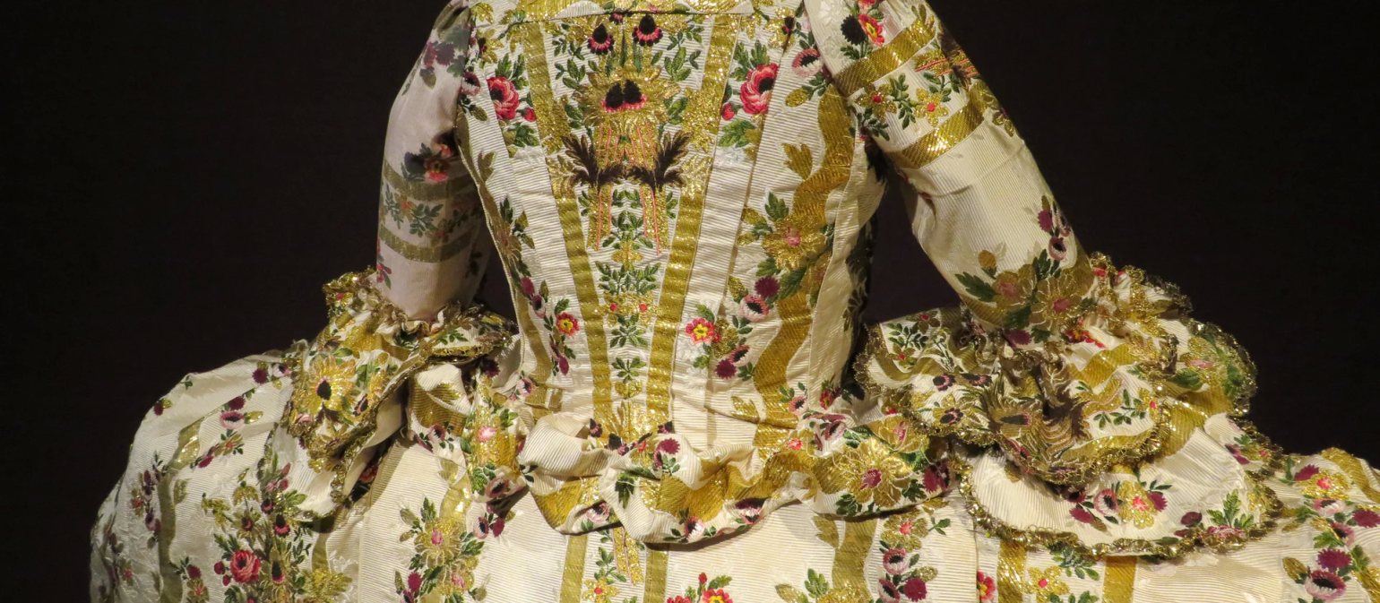 The back of a floral and gold detailed dress, part of ‘A Dress Fit for a King’ exhibition at Berrington Hall, Herefordshire, UK. The back of a floral and gold detailed dress, part of ‘A Dress Fit for a King’ exhibition at Berrington Hall, Herefordshire, UK.