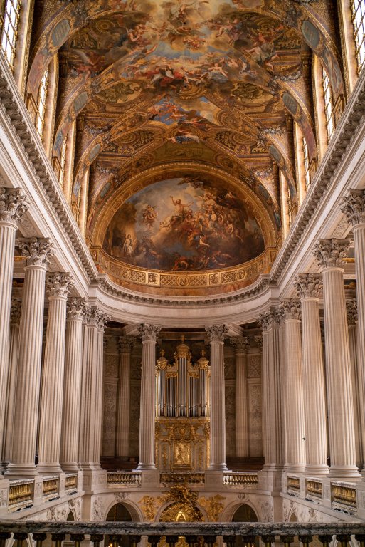 Painted ceilings and grand pillars with intricate detailing inside the Palace of Versailles.