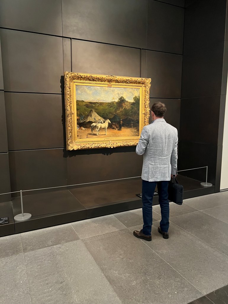 Series of paintings on display at Louvre Abu Dhabi, protected by museum barriers.