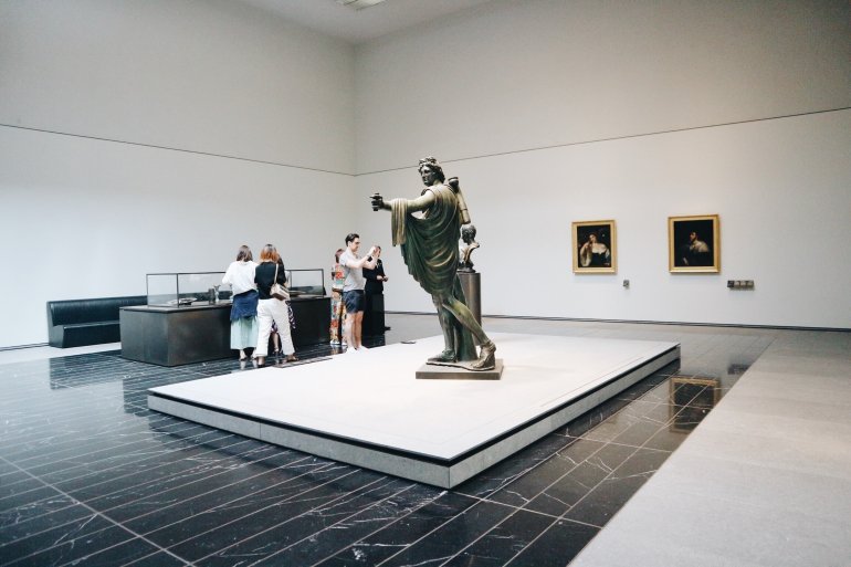 A bronze statue of a person, portrait artworks, and other artifacts on display at Louvre Abu Dhabi. A bronze statue of a person, portrait artworks, and other artifacts on display at Louvre Abu Dhabi.